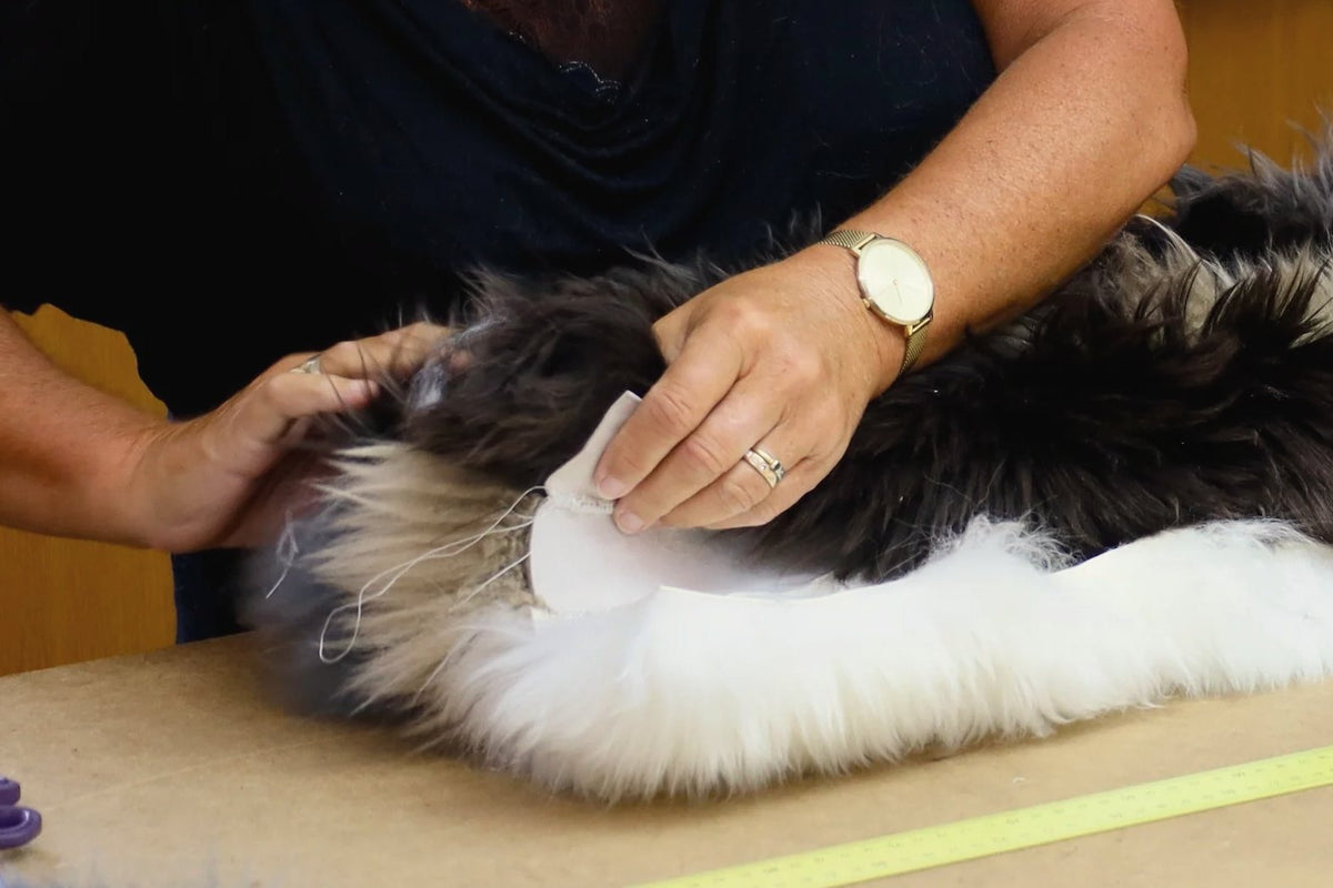 Hands checking the edge of a sheepskin before it is cut