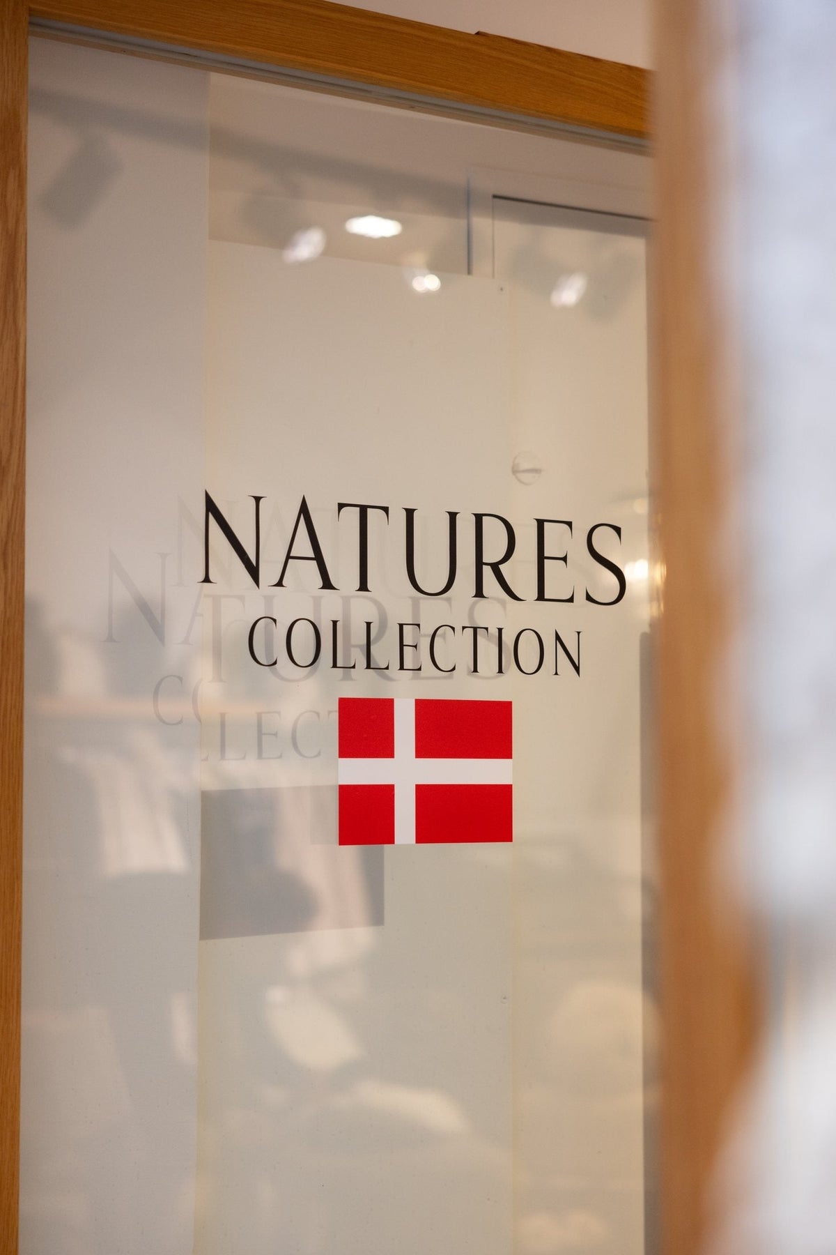 Natures Collection logo and the Danish flag on a glass door