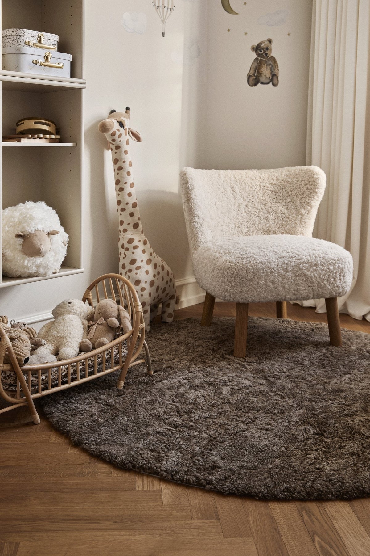 Round short-wool sheepskin rug in a nursery with a fluffy armchair and a toy giraffe